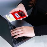 Mãos usando um cartão de crédito durante um pagamento online em um laptop.