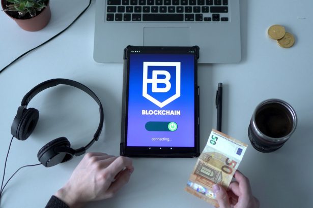 Tablet exibindo um aplicativo de blockchain ao lado de cédulas e ferramentas tecnológicas sobre uma mesa.
