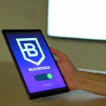 Mão segurando um tablet com uma representação de conexões de blockchain na tela.