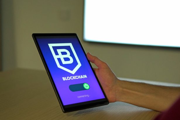 Mão segurando um tablet com uma representação de conexões de blockchain na tela.