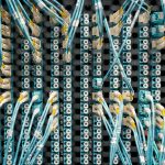 Cabos de fibra óptica conectados a portas de um servidor de dados moderno, vistos de cima