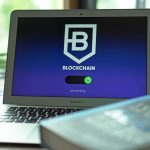 Laptop exibindo uma interface de blockchain com conexões digitais em uma tela escura.