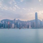Vista diurna do horizonte de Hong Kong a partir do Victoria Harbour, com arranha-céus e área portuária.