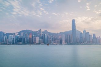 Vista diurna do horizonte de Hong Kong a partir do Victoria Harbour, com arranha-céus e área portuária.