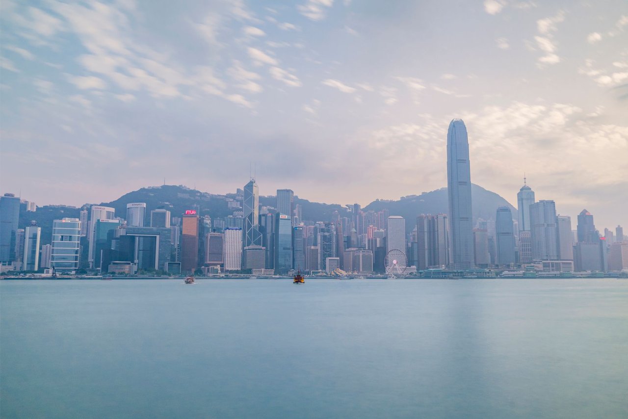 Vista diurna do horizonte de Hong Kong a partir do Victoria Harbour, com arranha-céus e área portuária.