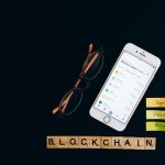 Smartphone exibindo informações do mercado de criptomoedas sobre fundo escuro, associado à tecnologia blockchain.